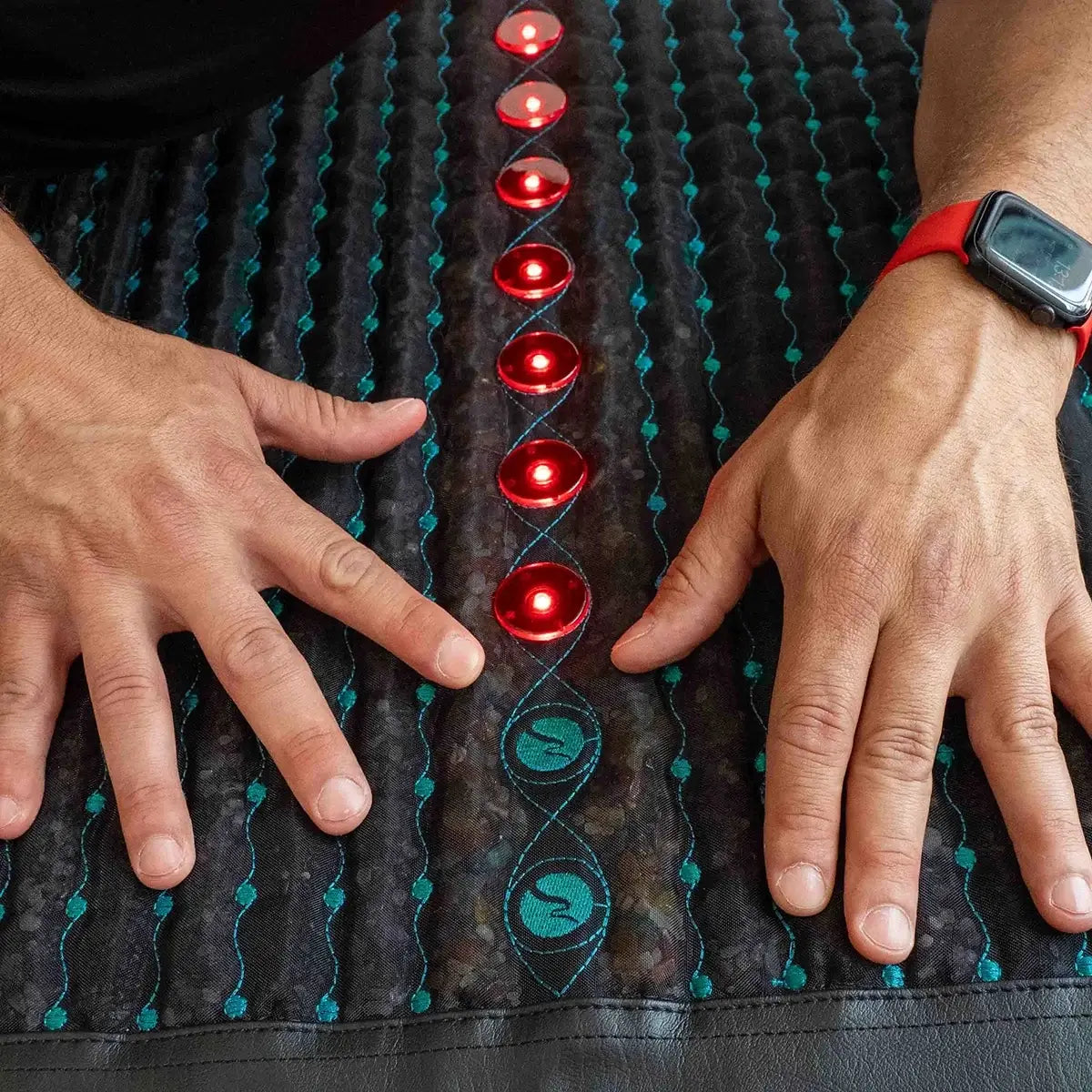 Nahaufnahme von Händen auf Rotlicht-Photonen und Edelsteinen der neowake Frequenzmatte